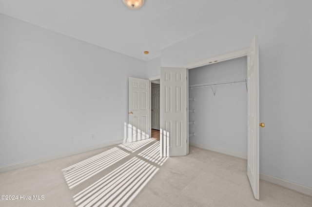 unfurnished bedroom featuring a closet and light colored carpet