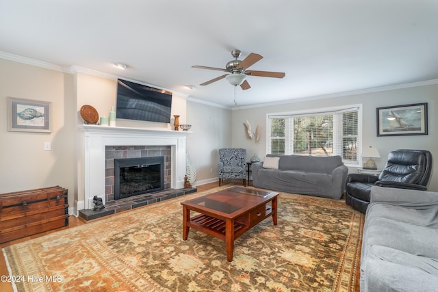 living room featuring wood-type flooring, ceiling fan, ornamental molding, and a tiled fireplace