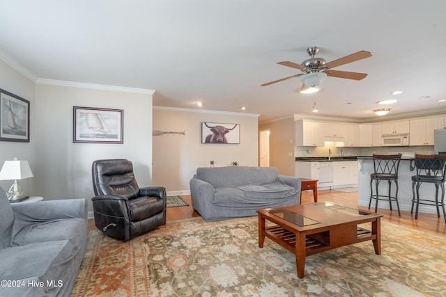 living room with light wood-type flooring, ceiling fan, ornamental molding, and sink