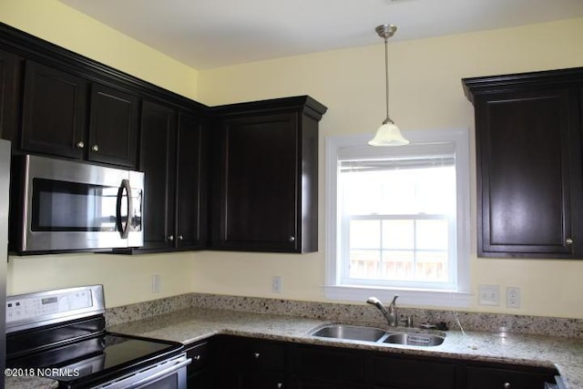 kitchen featuring range with electric cooktop, decorative light fixtures, light stone counters, and sink