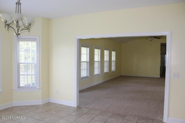 spare room with a notable chandelier, plenty of natural light, and light carpet