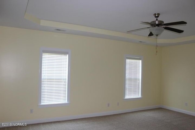 spare room with ceiling fan, a raised ceiling, and carpet floors