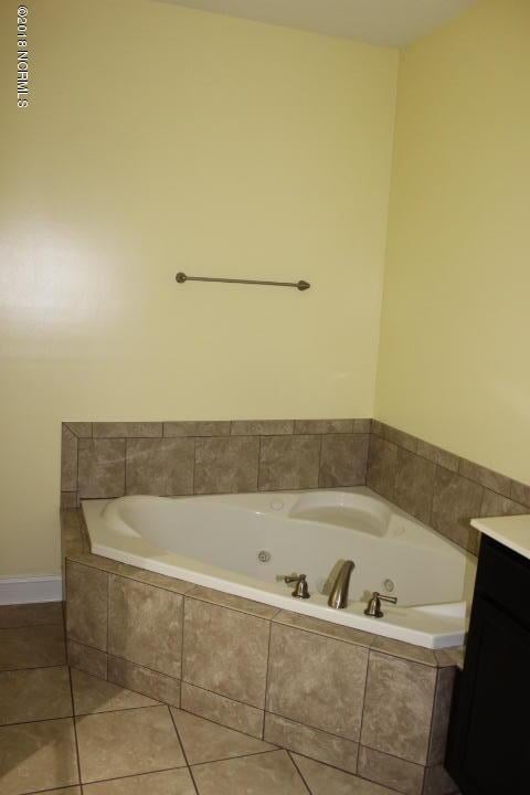 bathroom with tile patterned floors, tiled tub, and vanity