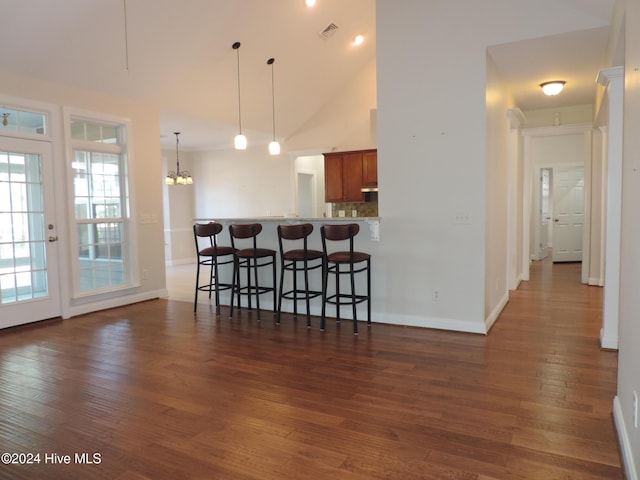 kitchen with kitchen peninsula, an inviting chandelier, dark wood-type flooring, and a breakfast bar area