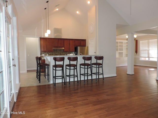 kitchen with dark hardwood / wood-style floors, stainless steel fridge, a kitchen bar, and high vaulted ceiling