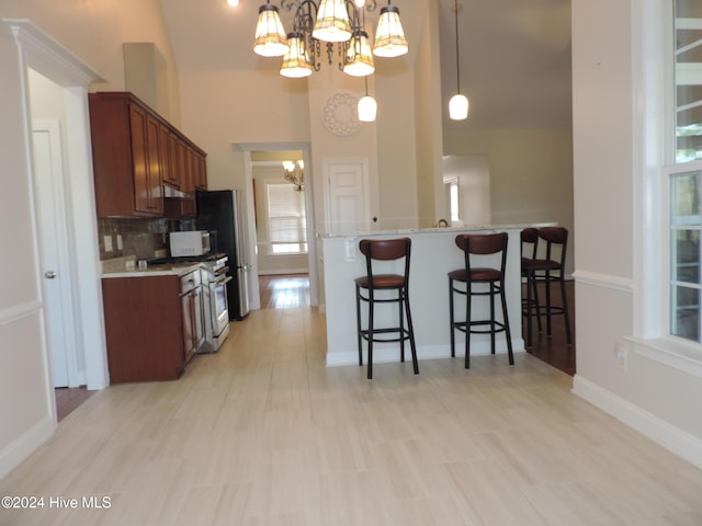 kitchen with white appliances, high vaulted ceiling, decorative backsplash, light stone countertops, and a notable chandelier