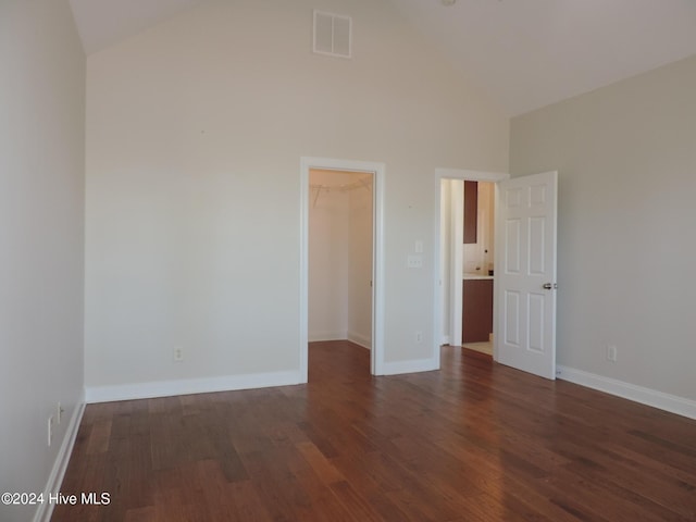 empty room with high vaulted ceiling and dark wood-type flooring