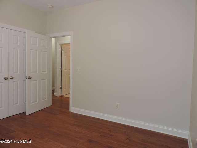 unfurnished bedroom with dark hardwood / wood-style floors and a closet