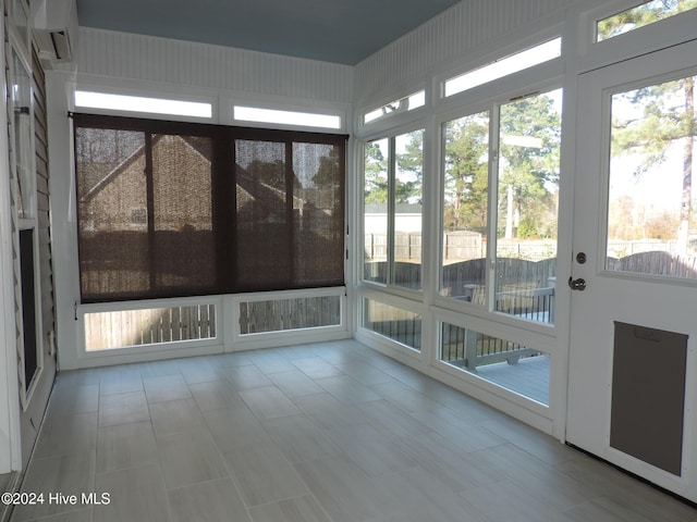 unfurnished sunroom with plenty of natural light and a wall mounted AC