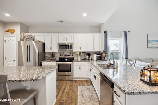 kitchen with white cabinetry, sink, stainless steel appliances, a kitchen breakfast bar, and dark hardwood / wood-style flooring