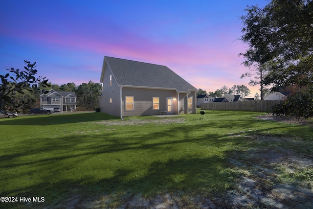 back house at dusk with a lawn