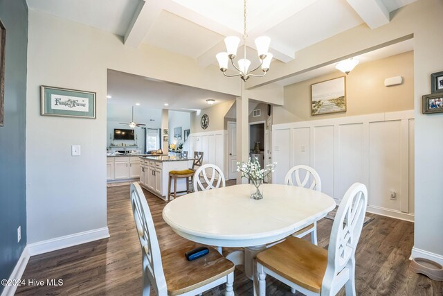 dining space featuring ceiling fan with notable chandelier, beam ceiling, and dark hardwood / wood-style flooring