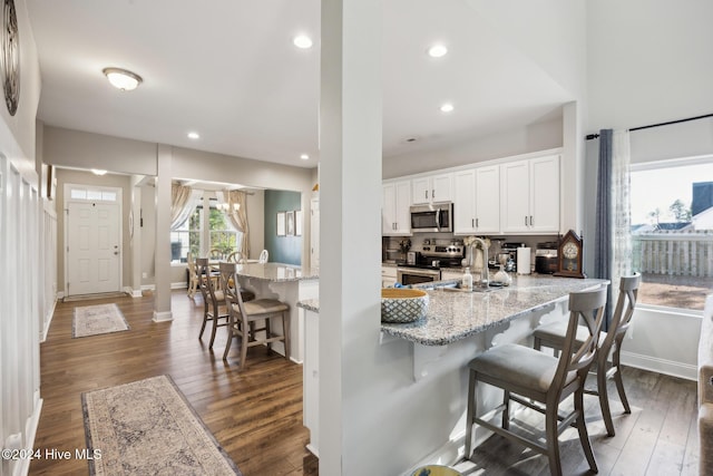 kitchen with a breakfast bar area, white cabinetry, dark hardwood / wood-style floors, and appliances with stainless steel finishes