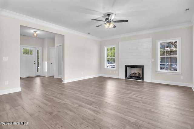 unfurnished living room featuring wood finished floors, ceiling fan, a fireplace, baseboards, and ornamental molding