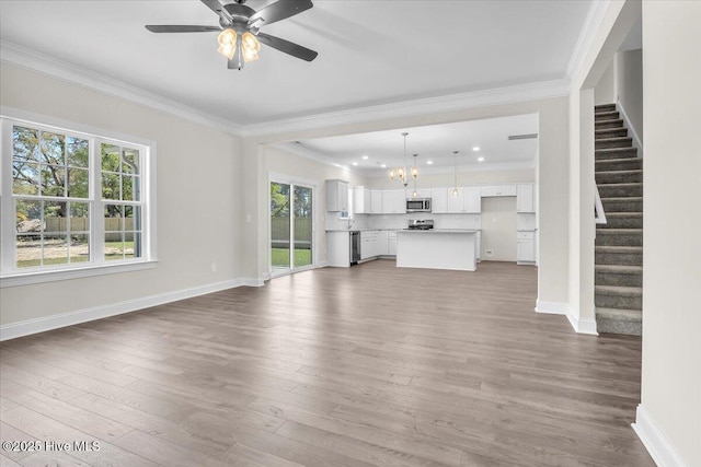unfurnished living room featuring plenty of natural light, stairs, baseboards, and wood finished floors