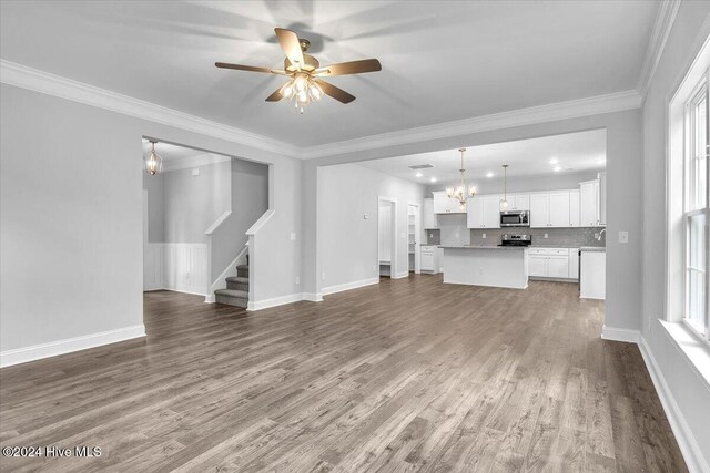 unfurnished living room with hardwood / wood-style flooring, plenty of natural light, ornamental molding, and ceiling fan with notable chandelier