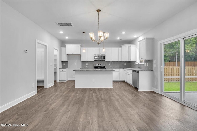 kitchen featuring white cabinets, appliances with stainless steel finishes, decorative light fixtures, and a kitchen island