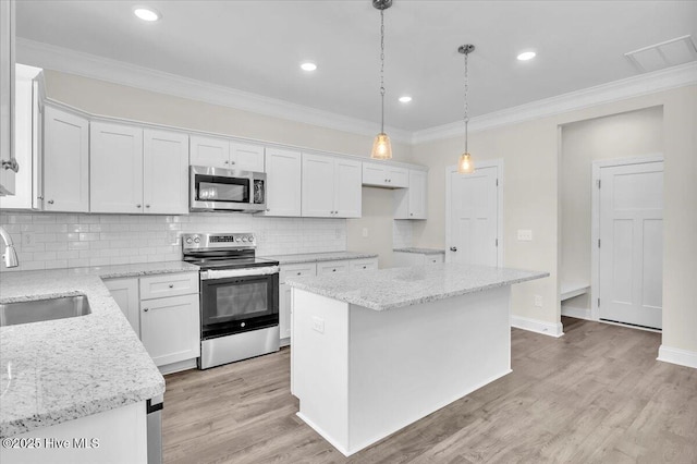 kitchen with stainless steel appliances, ornamental molding, a sink, tasteful backsplash, and white cabinetry