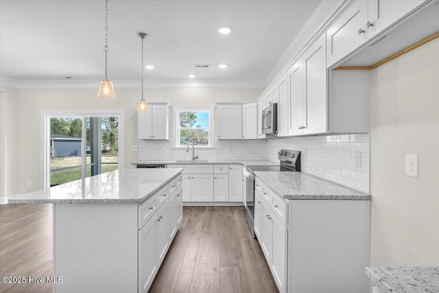 kitchen featuring a sink, light wood-style floors, stainless steel appliances, backsplash, and visible vents