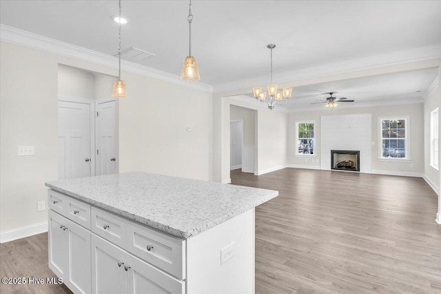 kitchen featuring light wood-style flooring, crown molding, a center island, and hanging light fixtures