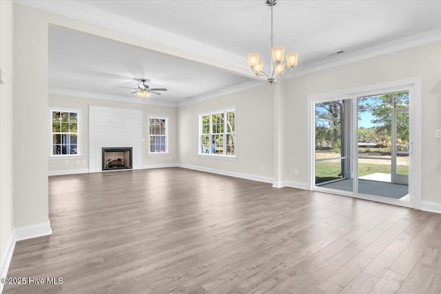 unfurnished living room featuring wood finished floors, crown molding, baseboards, a fireplace, and ceiling fan with notable chandelier