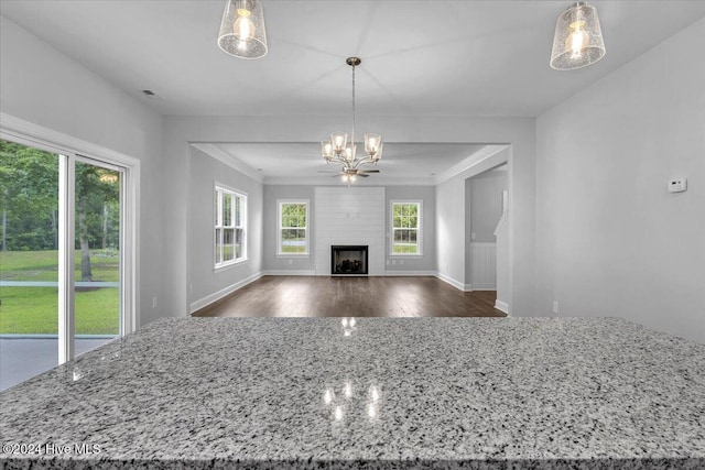 unfurnished living room with a fireplace, hardwood / wood-style floors, an inviting chandelier, and crown molding