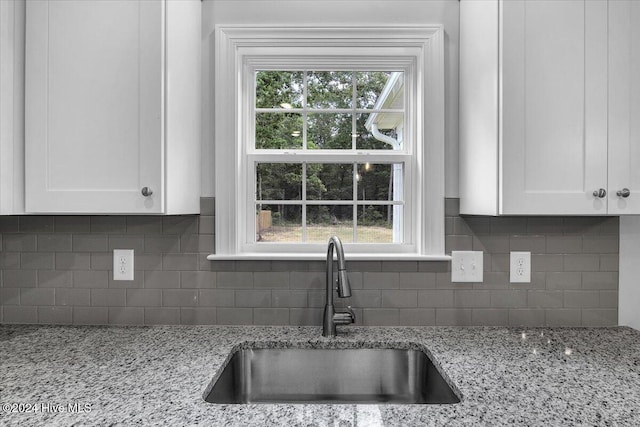 kitchen with white cabinets, decorative backsplash, and light stone countertops