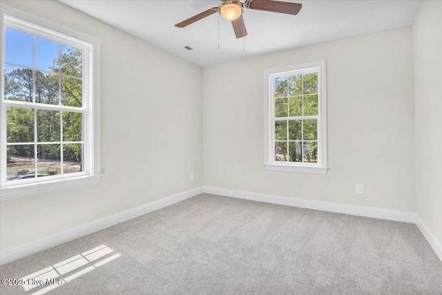 spare room with carpet floors, visible vents, and baseboards