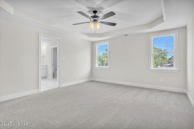 unfurnished bedroom with ensuite bath, baseboards, carpet flooring, and a raised ceiling