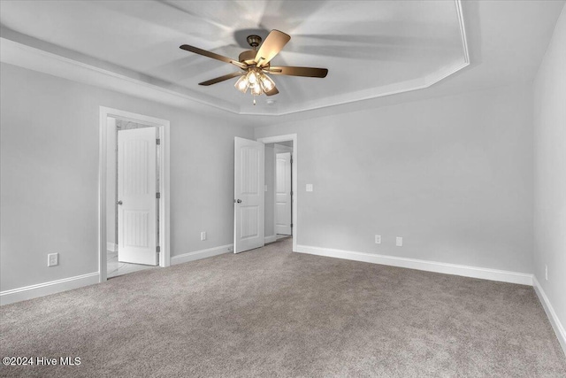 unfurnished room featuring carpet flooring, ceiling fan, and a raised ceiling