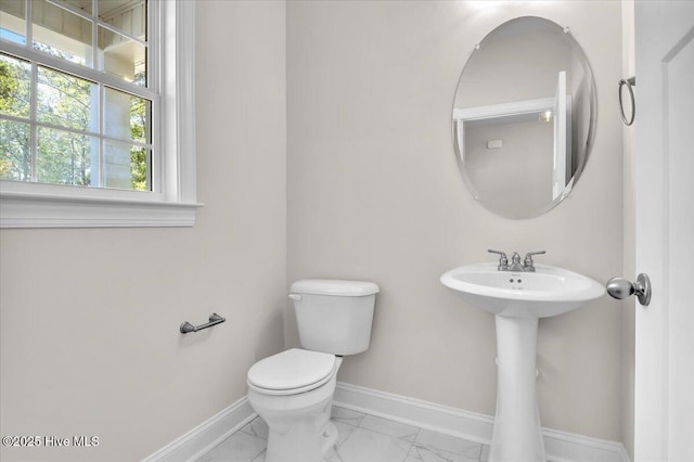 bathroom with marble finish floor, baseboards, toilet, and a sink