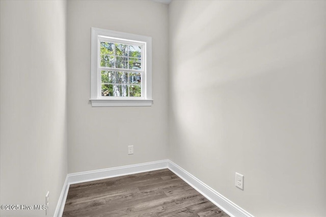 spare room featuring baseboards and dark wood-type flooring