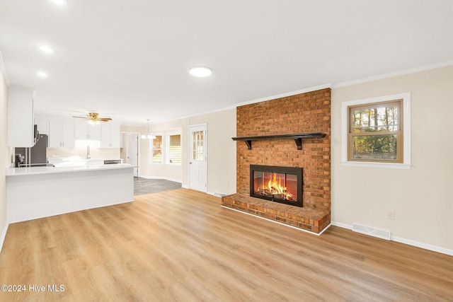 unfurnished living room featuring ceiling fan, a healthy amount of sunlight, a fireplace, and light hardwood / wood-style flooring