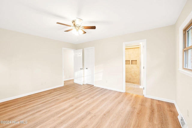 unfurnished bedroom with a closet, ensuite bath, light hardwood / wood-style flooring, and ceiling fan