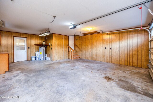 garage with water heater, wooden walls, and a garage door opener