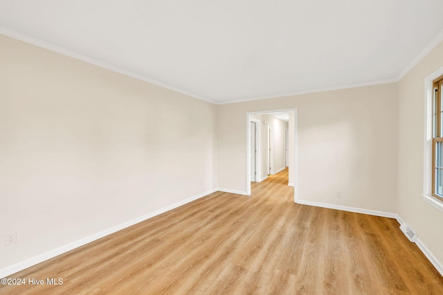 empty room with crown molding and light hardwood / wood-style floors