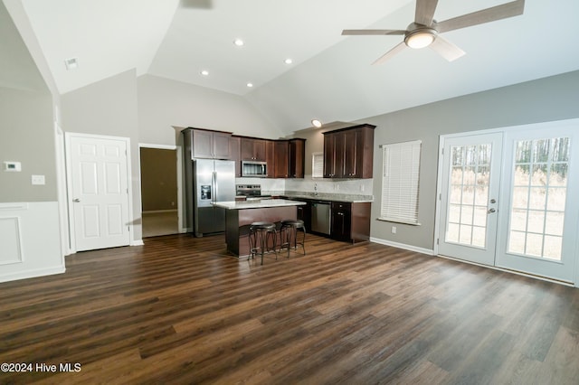 kitchen featuring dark wood-type flooring, a kitchen breakfast bar, ceiling fan, appliances with stainless steel finishes, and a kitchen island