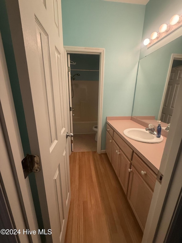 full bathroom with wood-type flooring, vanity, shower / bath combination, and toilet