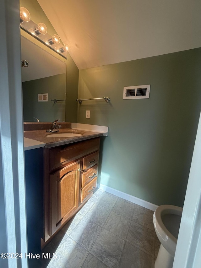 bathroom featuring vanity, lofted ceiling, and toilet