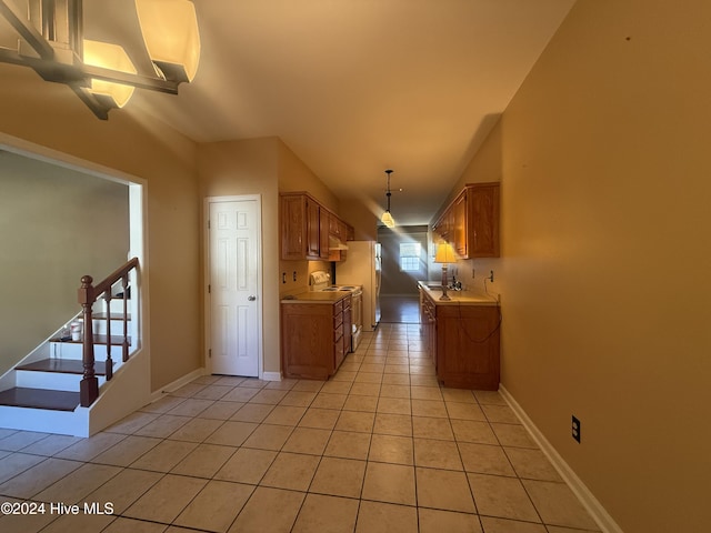 kitchen featuring white fridge, light tile patterned flooring, sink, and hanging light fixtures