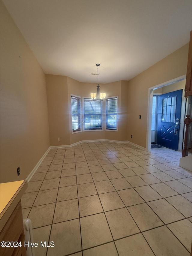 unfurnished dining area featuring light tile patterned floors and a notable chandelier