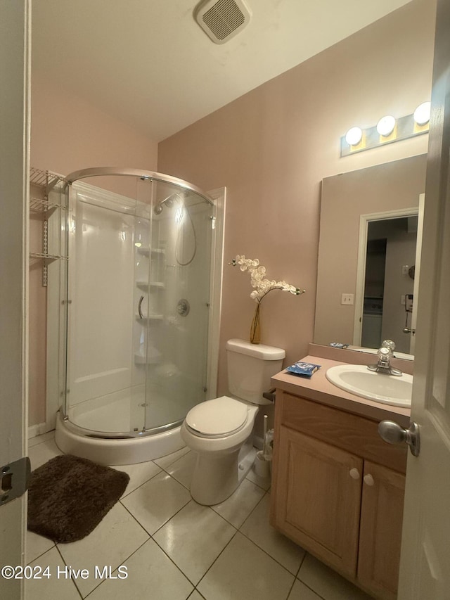 bathroom featuring tile patterned flooring, vanity, an enclosed shower, and toilet