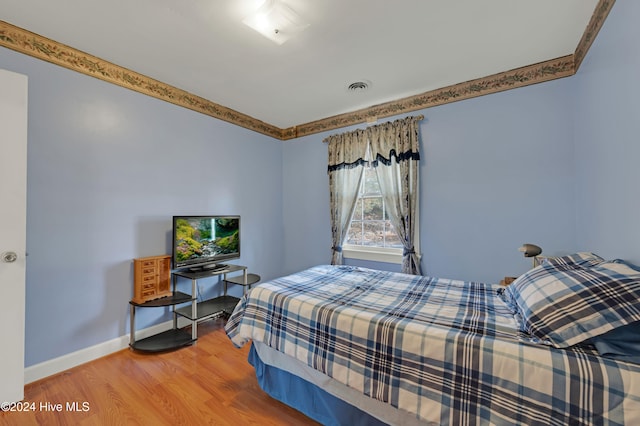 bedroom featuring hardwood / wood-style floors and ornamental molding