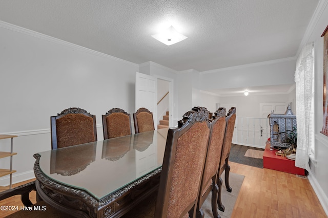 dining space with ornamental molding, a textured ceiling, and light wood-type flooring