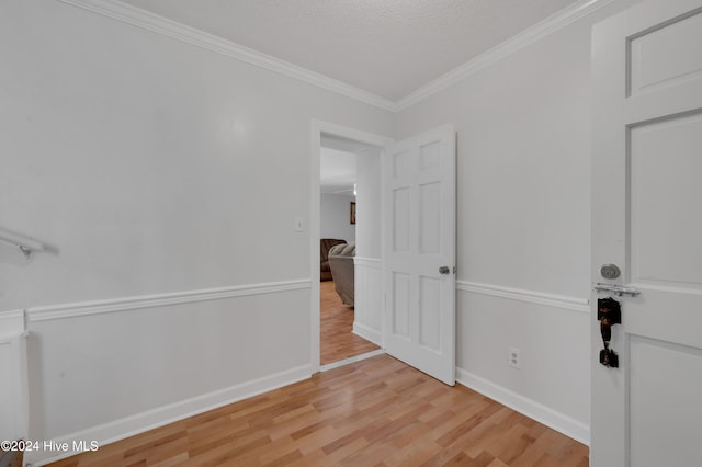 empty room featuring light hardwood / wood-style floors, a textured ceiling, and ornamental molding