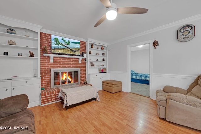 living room with ceiling fan, light hardwood / wood-style floors, crown molding, and a brick fireplace