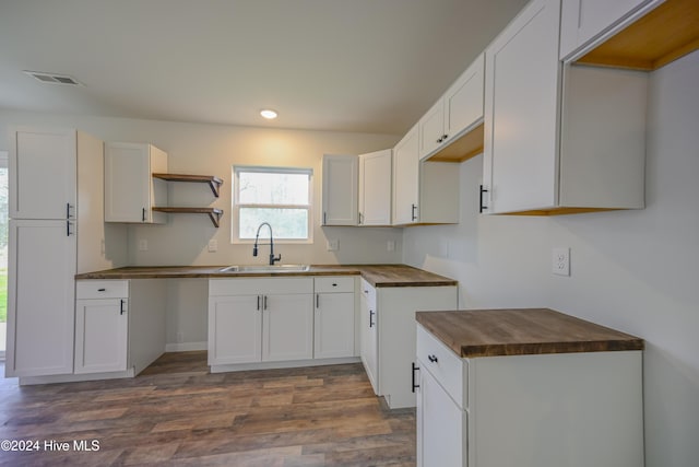 kitchen with butcher block countertops, sink, white cabinets, and dark hardwood / wood-style floors