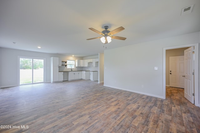 unfurnished living room featuring dark hardwood / wood-style floors, ceiling fan, and sink