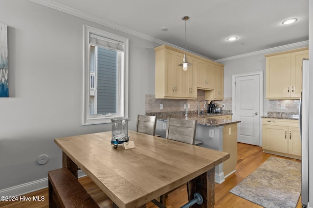 kitchen featuring sink, tasteful backsplash, light wood-type flooring, decorative light fixtures, and ornamental molding