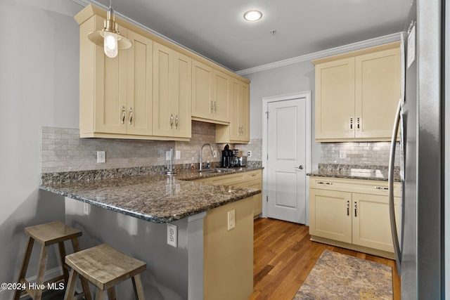 kitchen with stainless steel refrigerator, kitchen peninsula, decorative light fixtures, a breakfast bar area, and decorative backsplash